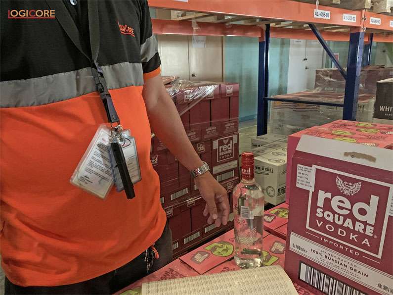 LogiCore warehouse staff putting labels on each liquor bottle